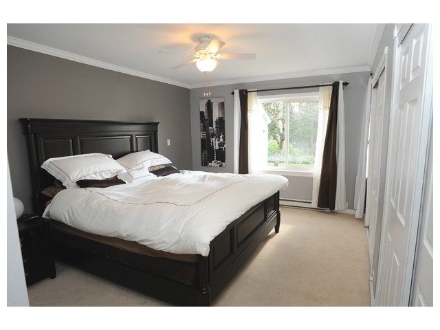 Spacious master bedroom with dark wood bed frame, neutral carpet, and large window with curtains. - 1889  Alderlynn Drive, North Vancouver