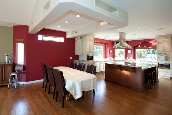 Bright dining area with hardwood floors and red walls, featuring a large table and modern decor. - 967 Roslyn Blvd., North Vancouver