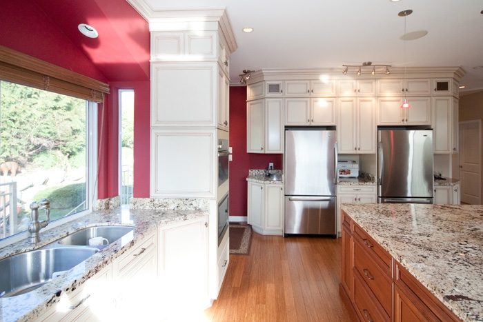 Bright kitchen with white cabinets, granite countertops, hardwood floors, and a city view. - 967 Roslyn Blvd., North Vancouver