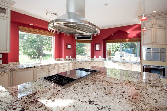 Bright kitchen with granite countertops and red walls, featuring a large island and stainless steel appliances. - 967 Roslyn Blvd., North Vancouver