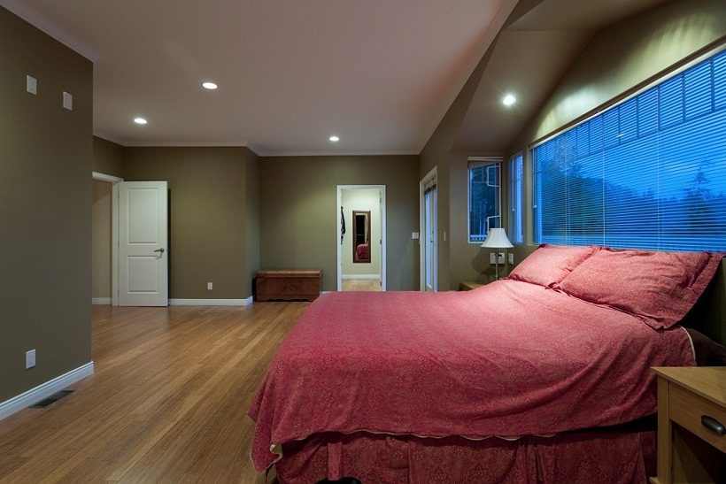 Spacious bedroom with hardwood floors, large windows, and a cozy bed setup. - 967 Roslyn Blvd., North Vancouver