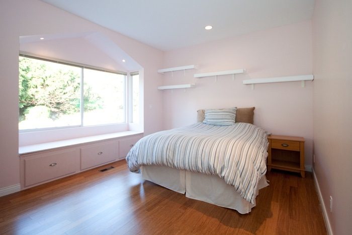 Bright bedroom with hardwood floors, large window view, and built-in shelving. - 967 Roslyn Blvd., North Vancouver