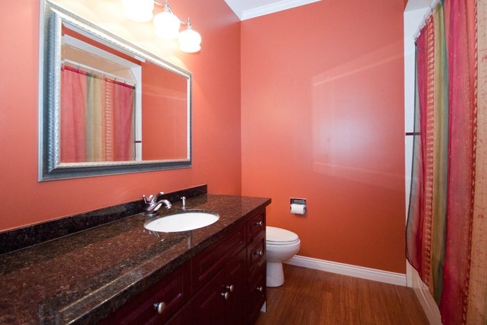 Bathroom with granite countertops, hardwood floors, and a red wall. - 967 Roslyn Blvd., North Vancouver