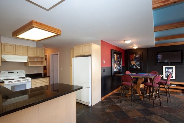 Bright kitchen with black countertops and wooden cabinets, leading into a dining area with colorful walls and a cozy...