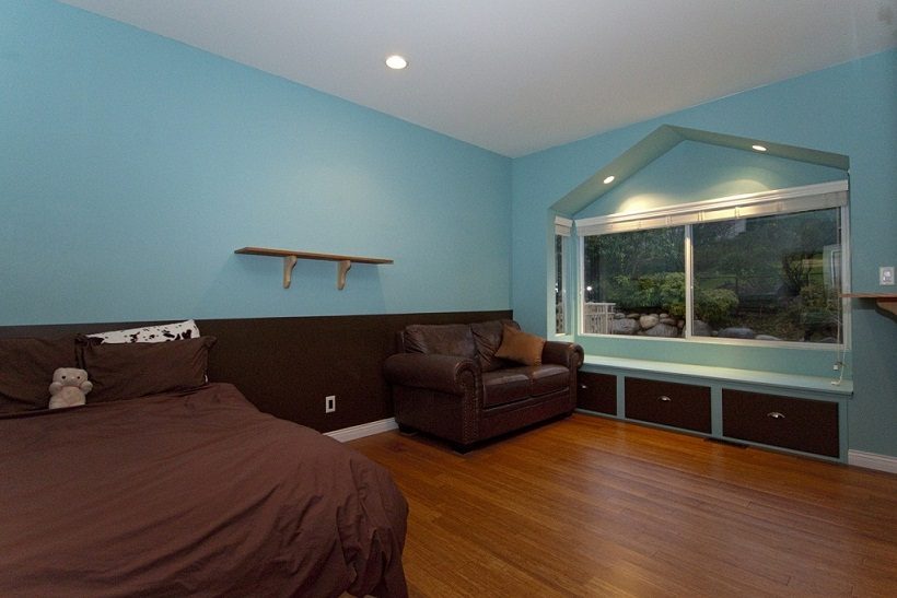 Bright bedroom with hardwood floors, large window, and brown furniture. - 967 Roslyn Blvd., North Vancouver