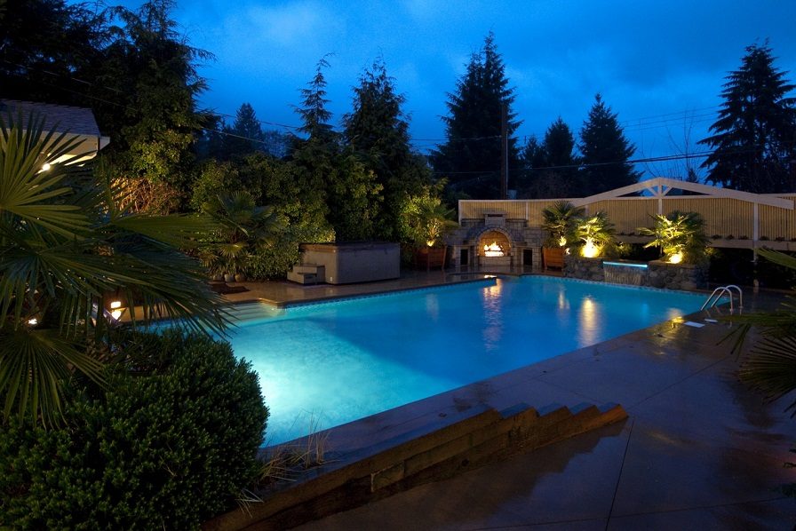 Spacious pool area with illuminated water and surrounding greenery. - 967 Roslyn Blvd., North Vancouver