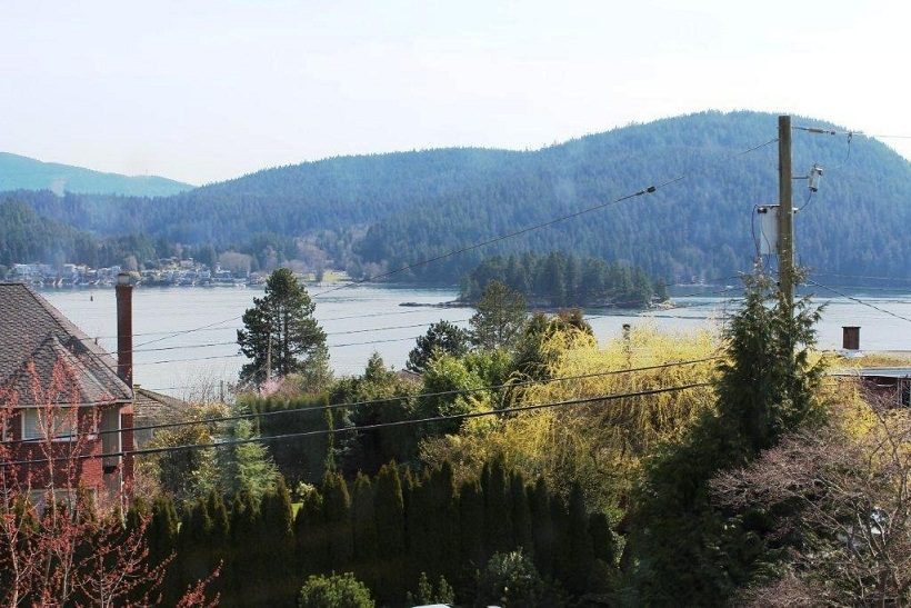 Bright living room with a view of the lake and forested hills. - 967 Roslyn Blvd., North Vancouver
