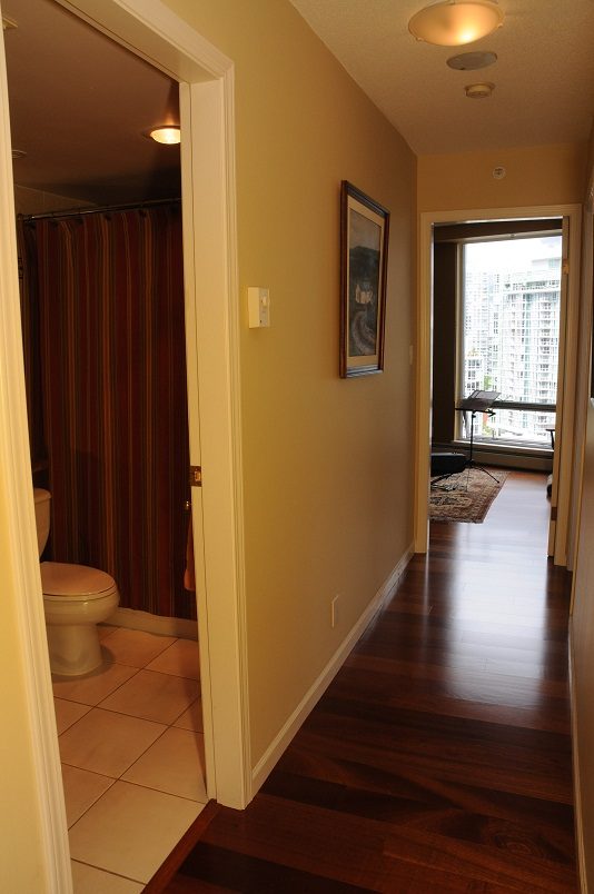 Furnished hallway with hardwood floors leading to a bathroom and city view. - 2002 - 1228 Marinaside Crescent, Vancouver Downtown