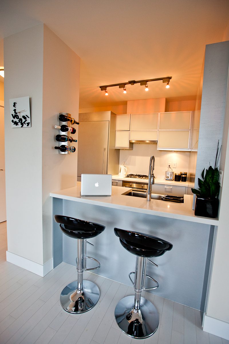 Bright kitchen with white countertops, black bar stools, and wine rack. - 2002 - 1228 Marinaside Crescent, Vancouver Downtown