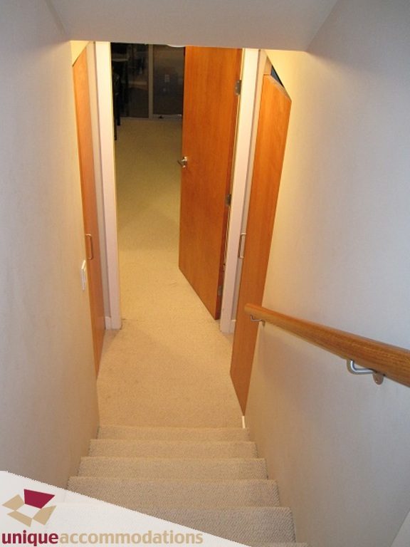 Furnished hallway leading to bedrooms with carpeted stairs and wooden doors. - 6-1250 West 6th Ave, Vancouver West Side