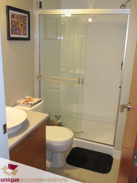 Bathroom with white subway tile, glass shower door, and black bath mat. - 6-1250 West 6th Ave, Vancouver West Side