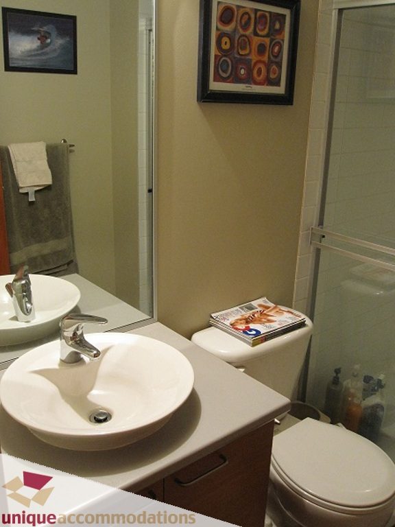 Bright bathroom with modern sink, framed artwork, and glass shower door. - 6-1250 West 6th Ave, Vancouver West Side