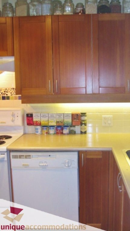 Bright kitchen with wooden cabinets, white countertops, and a tiled backsplash. - 306-3727 West 10th Ave, Vancouver West Side