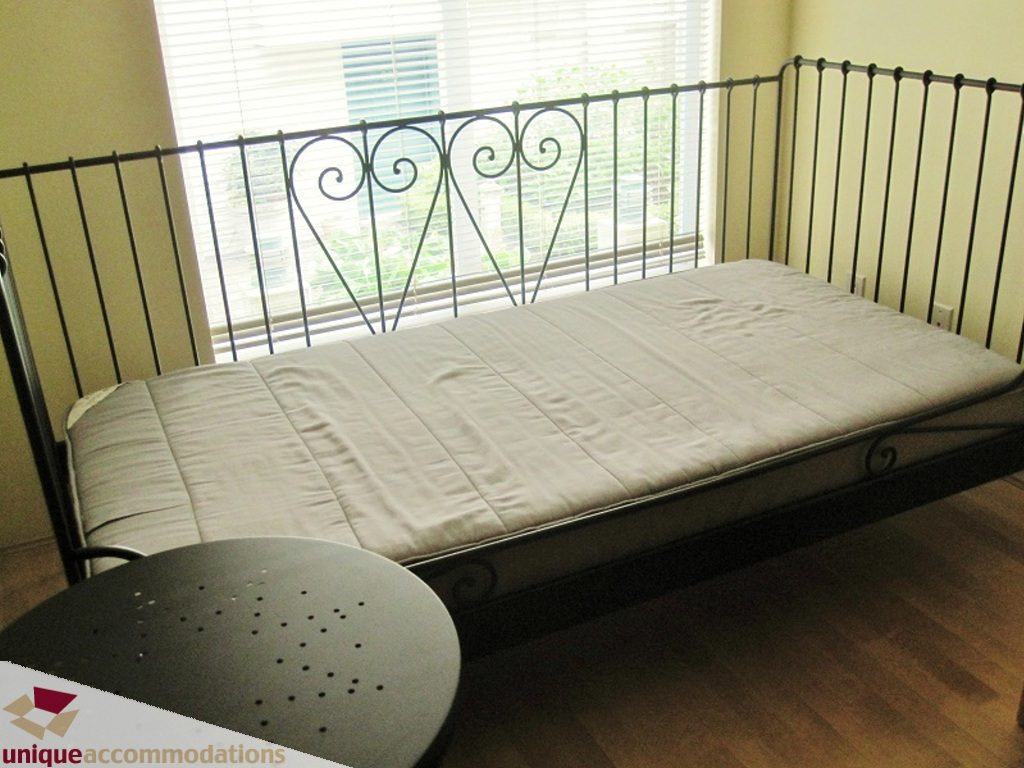 Bright bedroom with hardwood floors and a metal bed frame, featuring a balcony view. - 306-3727 West 10th Ave, Vancouver West Side
