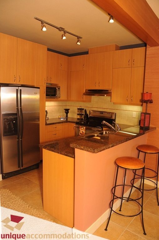 Bright kitchen with granite countertops, wooden cabinets, and stainless steel appliances. - 103-580 Raven Woods Drive, North Vancouver
