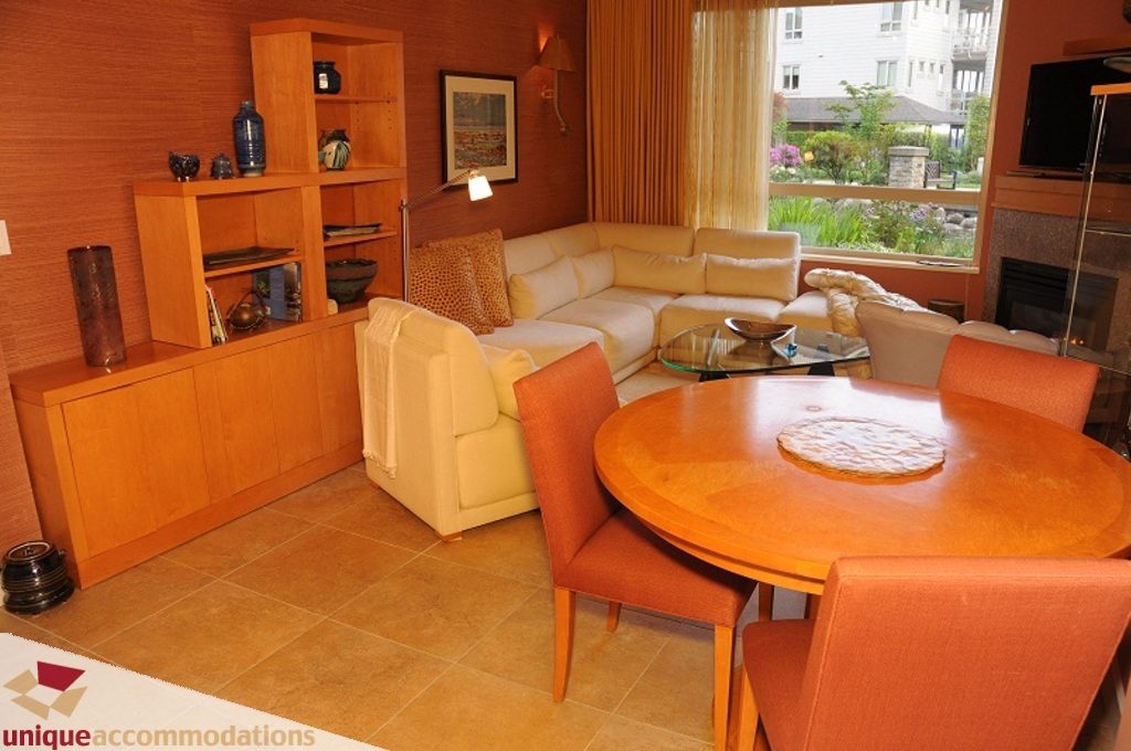 Furnished living room with a cozy sectional, large window, and modern decor. - 103-580 Raven Woods Drive, North Vancouver