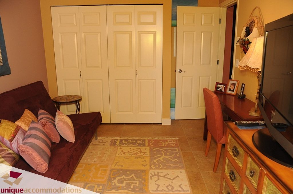 Furnished living room with patterned rug, hardwood floors, and a cozy sofa. - 103-580 Raven Woods Drive, North Vancouver