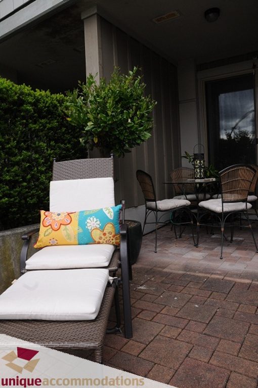 Furnished patio with outdoor furniture and colorful cushions. - 103-580 Raven Woods Drive, North Vancouver