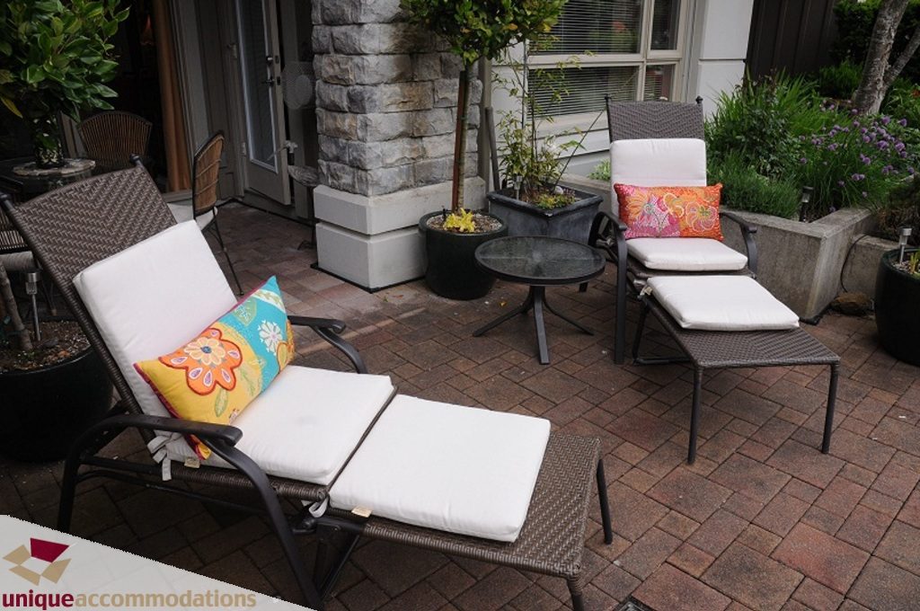 Furnished patio with outdoor furniture, potted plants, and colorful cushions. - 103-580 Raven Woods Drive, North Vancouver