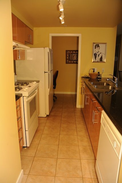 Bright kitchen with tiled floors, white appliances, and a framed portrait on the wall. - 1501 -1077 Marinaside Crescent, Vancouver Downtown