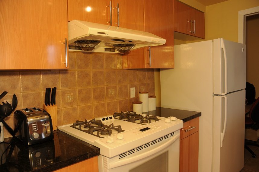 Bright kitchen with gas stove, white appliances, and wooden cabinets. - 1501 -1077 Marinaside Crescent, Vancouver Downtown
