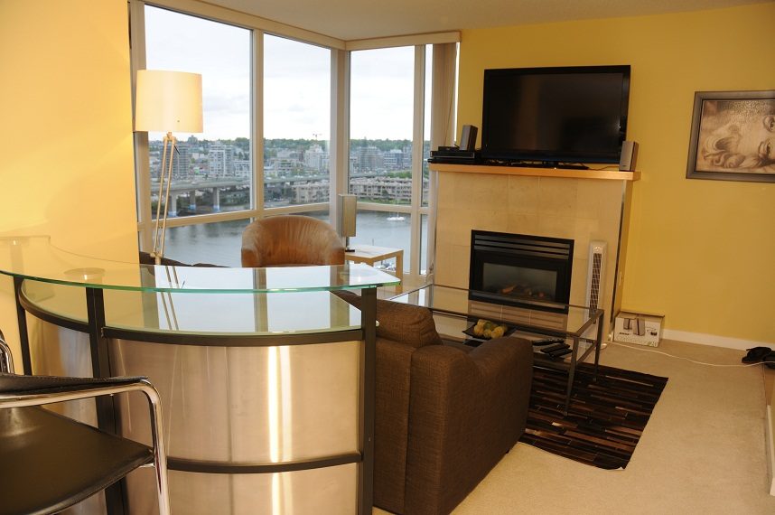 Bright living room with glass table, city view, and modern fireplace. - 1501 -1077 Marinaside Crescent, Vancouver Downtown