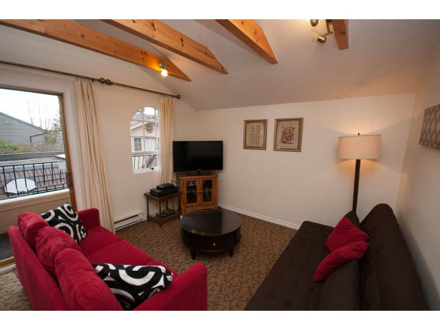 Bright living room with red sofas, wooden beams, and a city view. - Cottage - Sinclair Street, West Vancouver