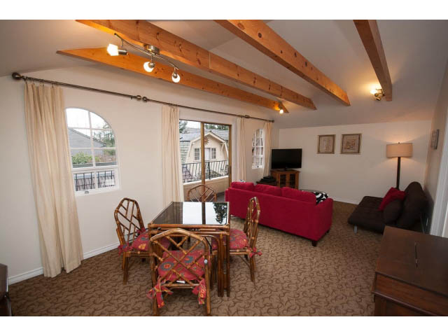 Furnished living room with exposed beams, red furniture, and large windows. - Cottage - Sinclair Street, West Vancouver