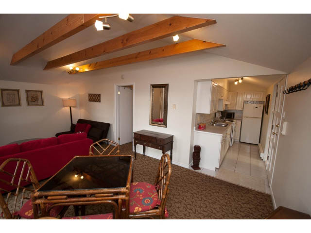 Furnished living room with exposed wooden beams and red couches. - Cottage - Sinclair Street, West Vancouver
