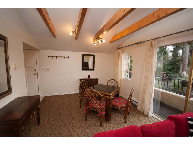 Furnished living room with wooden beams, red couch, and balcony view. - Cottage - Sinclair Street, West Vancouver