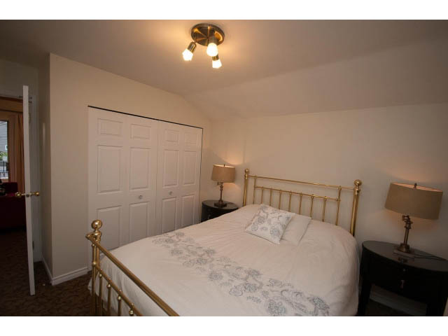 Bright bedroom with gold-framed beds and white bedding, featuring a ceiling light and bedside lamps. - Cottage - Sinclair Street, West Vancouver