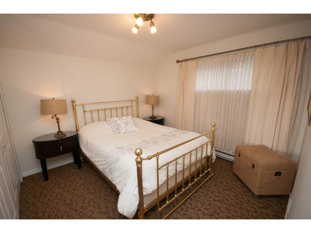 Bright bedroom with gold bed frame and patterned carpet. - Cottage - Sinclair Street, West Vancouver