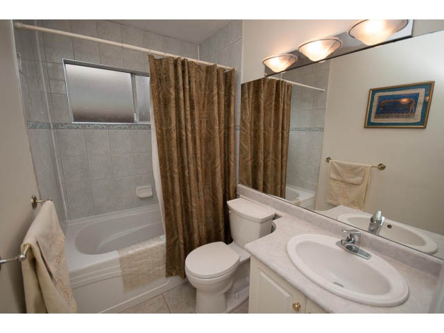Bathroom with white countertop, gold shower curtain, and wall-mounted lights. - Cottage - Sinclair Street, West Vancouver