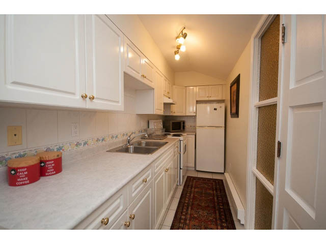 Bright kitchen with white cabinets, granite countertops, and a red coffee can. - Cottage - Sinclair Street, West Vancouver