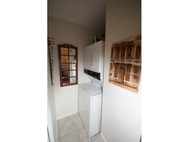 Bright kitchen with white cabinets and tiled floor, small window view. - Cottage - Sinclair Street, West Vancouver