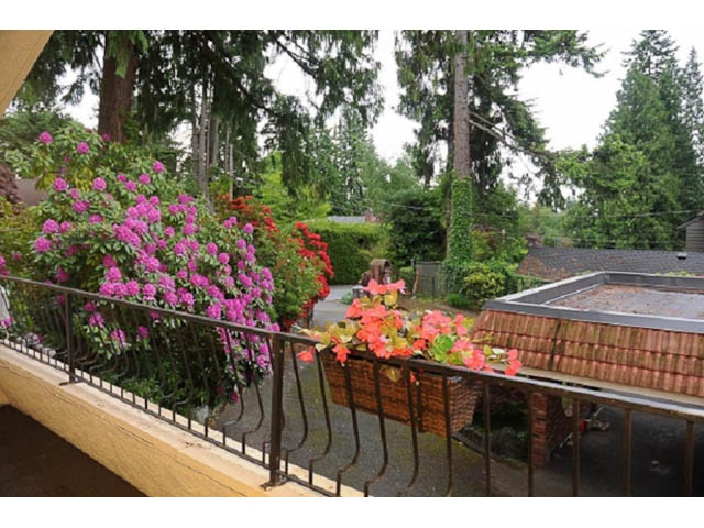Furnished balcony with vibrant pink flowers and brick wall. - Cottage - Sinclair Street, West Vancouver