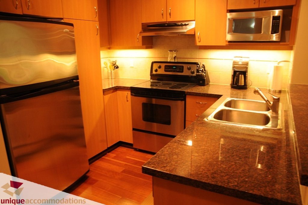 Bright kitchen with granite countertops, hardwood floors, and stainless steel appliances. - 212- 580 Raven Woods Drive, North Vancouver