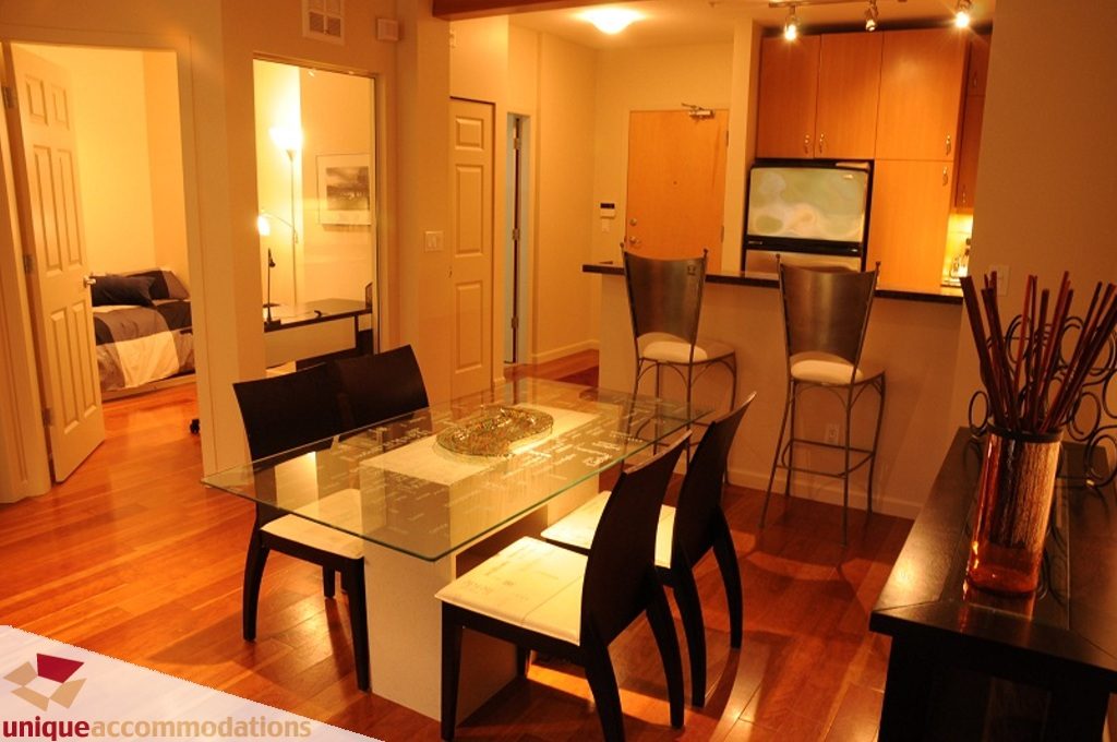 Furnished dining area with glass table, modern chairs, and hardwood floors. - 212- 580 Raven Woods Drive, North Vancouver