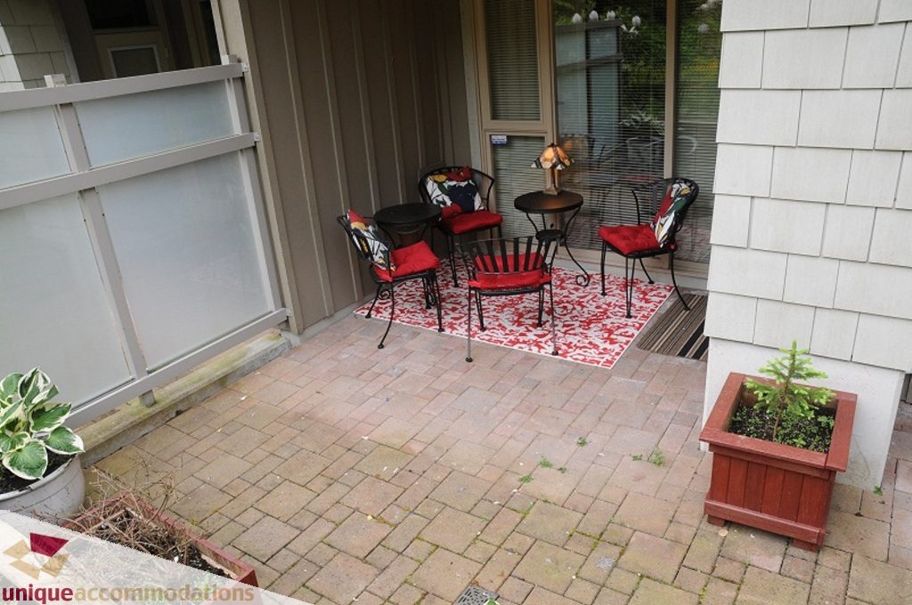 Furnished patio with red cushions, outdoor furniture, and potted plants. - 212- 580 Raven Woods Drive, North Vancouver