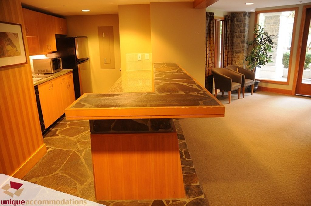 Bright kitchen with granite countertops and hardwood floors, leading to a cozy living area with a stone fireplace and...