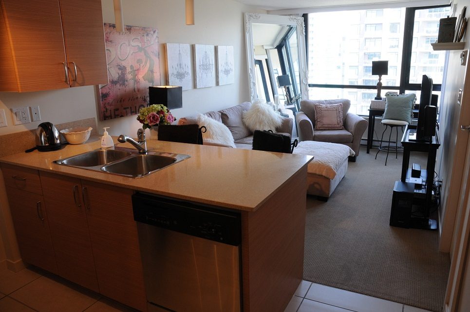 Bright kitchen with stainless steel appliances and a cozy living area featuring a city view. - 2605 - 928 Homer Street, Vancouver Downtown
