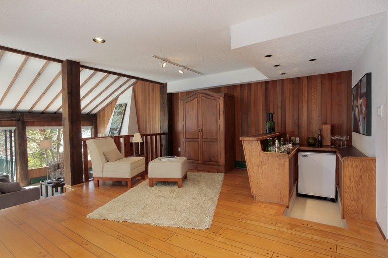 Bright kitchen with wooden cabinets, hardwood floors, and a cozy living area with a shag rug and modern furniture.