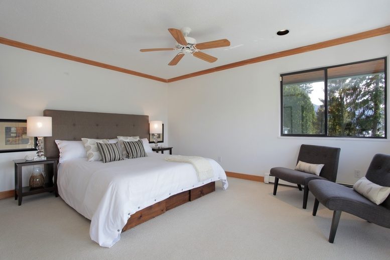 Spacious bedroom with large windows, modern furniture, and a ceiling fan. - 2758 Panorama Drive, North Vancouver