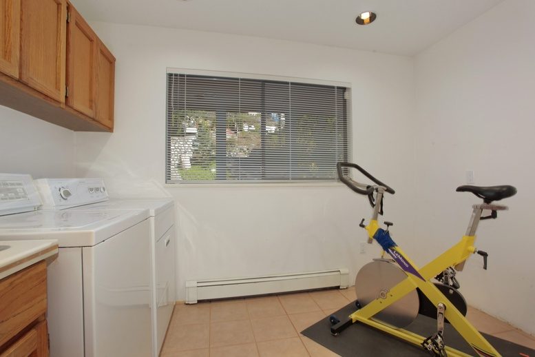 Bright laundry room with a window view, counter space, and a yellow exercise bike. - 2758 Panorama Drive, North Vancouver