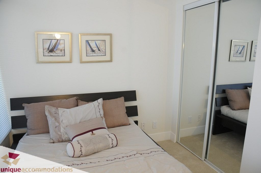 Furnished bedroom with modern decor, large closet, and framed artwork. - 3401 - 888 Homer Street, Vancouver Downtown