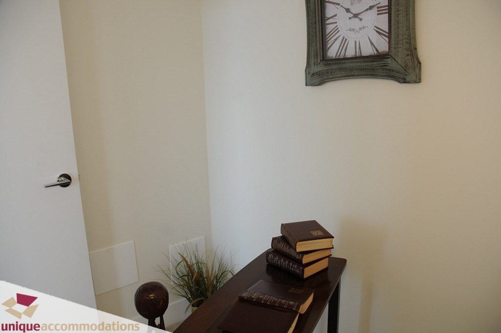 Bright entryway with a stack of books and a vintage clock, leading to a cozy living space. - 3401 - 888 Homer Street, Vancouver Downtown