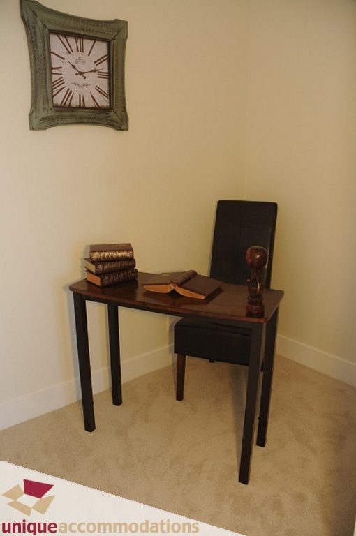 Bright study nook with a clock, books, and a chair. - 3401 - 888 Homer Street, Vancouver Downtown