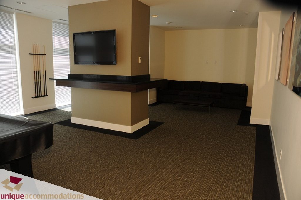 Living room with dark wood countertops and a large sectional sofa. - 3401 - 888 Homer Street, Vancouver Downtown
