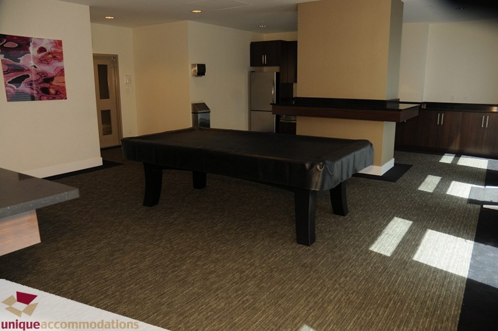 Furnished living room with pool table, modern kitchen counter, and natural light. - 3401 - 888 Homer Street, Vancouver Downtown