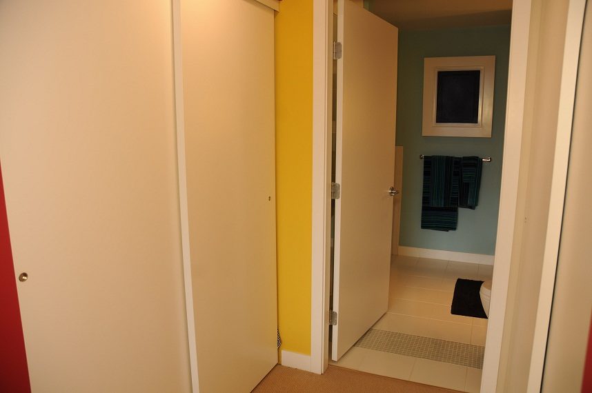 Bright hallway leading to a cozy bathroom with teal walls and a framed artwork. - 903-718 Main Street, Vancouver Downtown